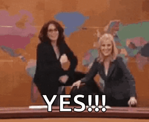 two women are sitting at a table and one of them is laughing and the other is saying yes !
