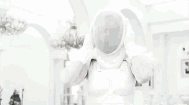 a woman in a white dress is standing in a white room