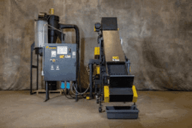 a blue and yellow machine in a factory with a conveyor belt attached to it .