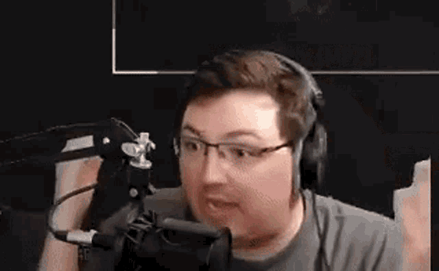 a man wearing headphones and glasses is sitting in front of a microphone .