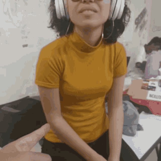 a woman wearing headphones and a yellow shirt is sitting in front of a nolution box