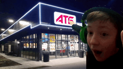 a boy wearing green headphones is standing in front of a store that says ats