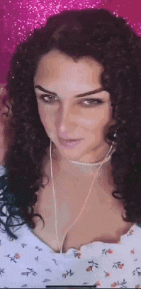 a woman with curly hair is wearing earphones and a choker necklace .