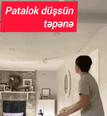 a man throws a frisbee in front of a sign that says patalok düşsün tapana