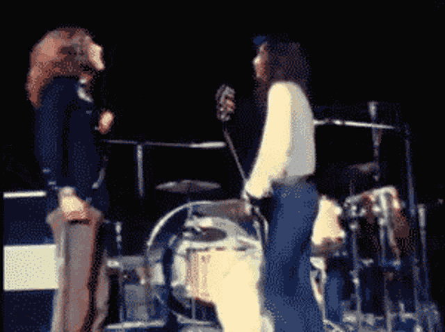 a man playing a guitar and another man playing drums on a stage