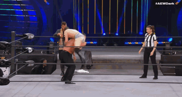 a wrestler is being lifted in the air by another wrestler while a referee watches during a wrestling match