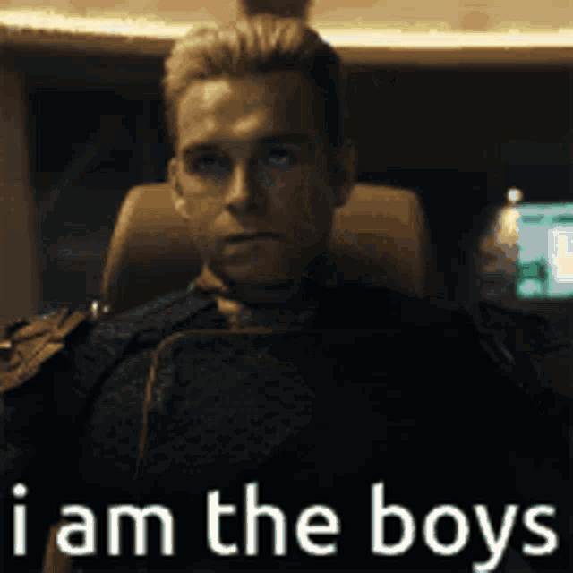 a man is sitting in a chair with the words i am the boys behind him .