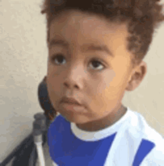 a young boy is wearing a blue and white bib and making a funny face .