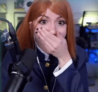 a woman with red hair is covering her mouth with her hand while standing in front of a microphone in a room .