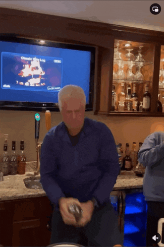a man in a blue shirt is shaking a can in front of a tv screen that says uv