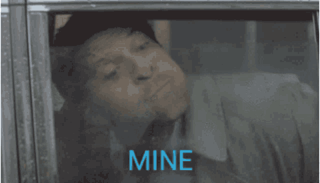 a man is laying in a car and the word mine is on the screen
