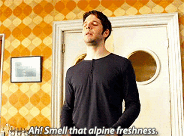 a man in a black shirt says " ah smell that alpine freshness " in front of a door