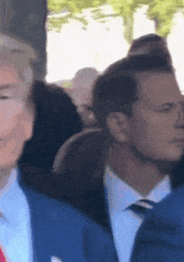 a man in a blue suit and tie is standing in a crowd .