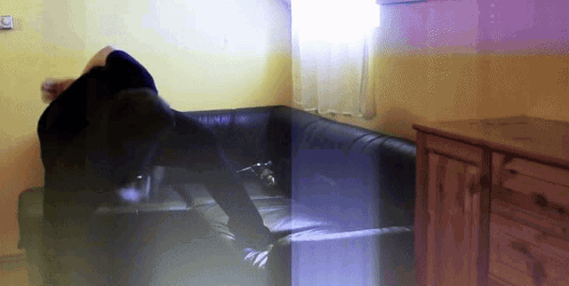 a blurry picture of a person sitting on a couch in a room
