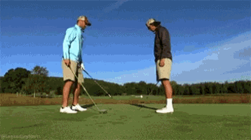 two men are playing golf on a golf course and one of them is holding a golf club .