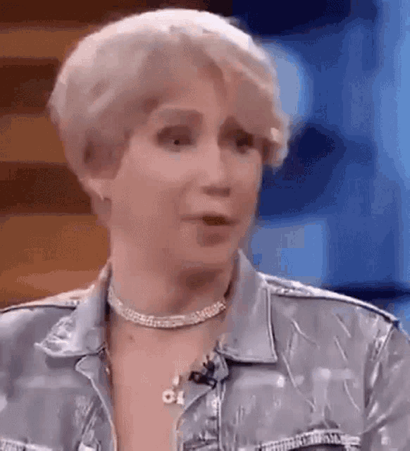 a woman wearing a denim jacket and a choker is talking on a television show .