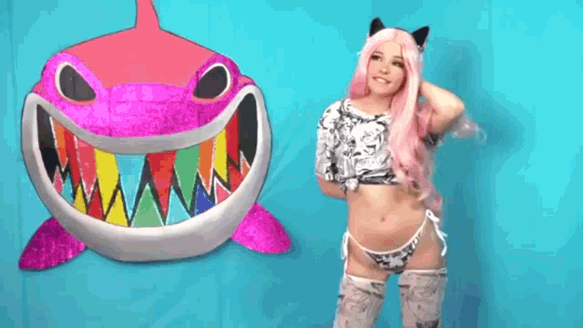 a woman in a costume is standing in front of a shark .
