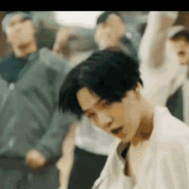 a man in a white shirt is standing in front of a crowd of people dancing .