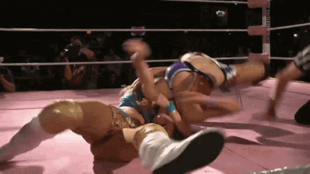 two women are wrestling in a ring and one of them is wearing a blue and gold outfit