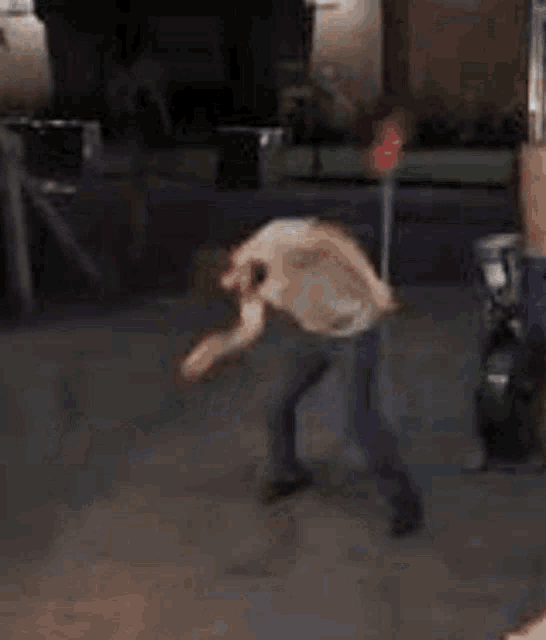 a man is kneeling down in front of a green car holding a broom .