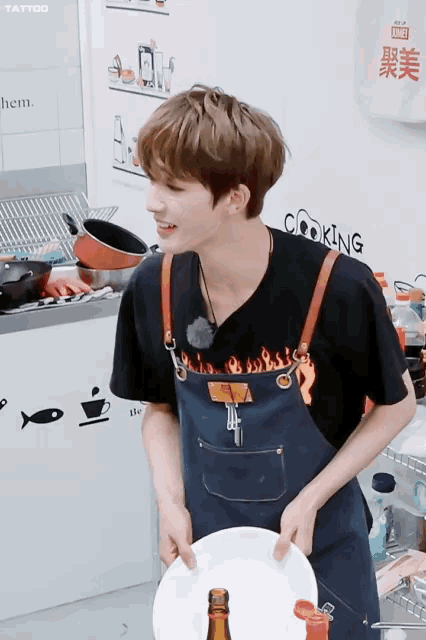 a man wearing a black shirt with flames on it and an apron with the word cooking on it