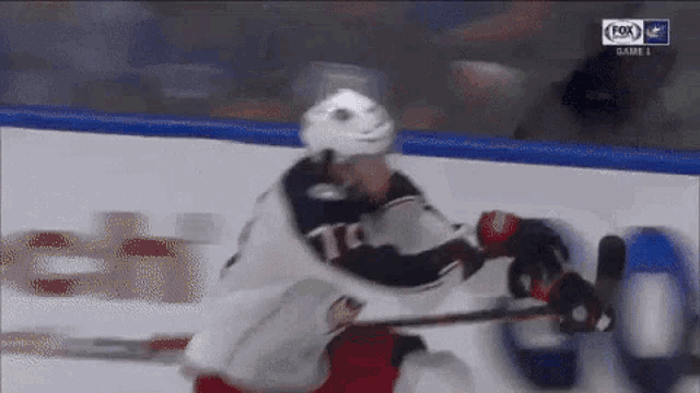 a hockey player is holding a puck in his hand while another player tries to block the puck .