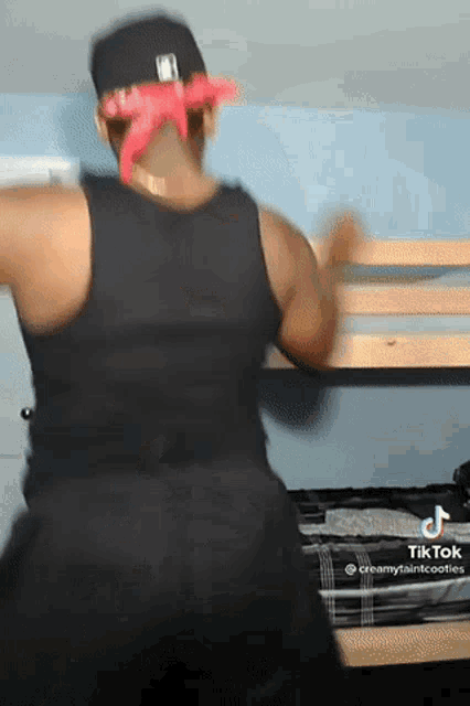 a man wearing a black tank top and a red bandana is dancing in front of a bunk bed ..