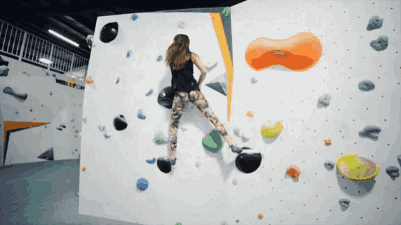 a woman climbs up a climbing wall with the word valley on the wall