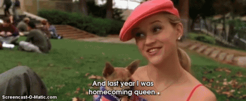a woman in a red hat is holding a small dog and saying and last year i was homecoming queen .