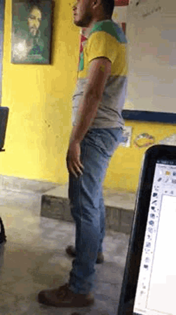 a man is standing in a room next to a laptop computer .