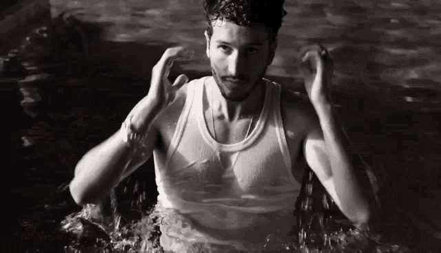 a man in a tank top is swimming in a pool