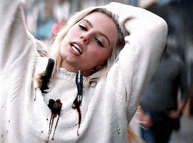 a woman is wearing a white sweater with blood coming out of it