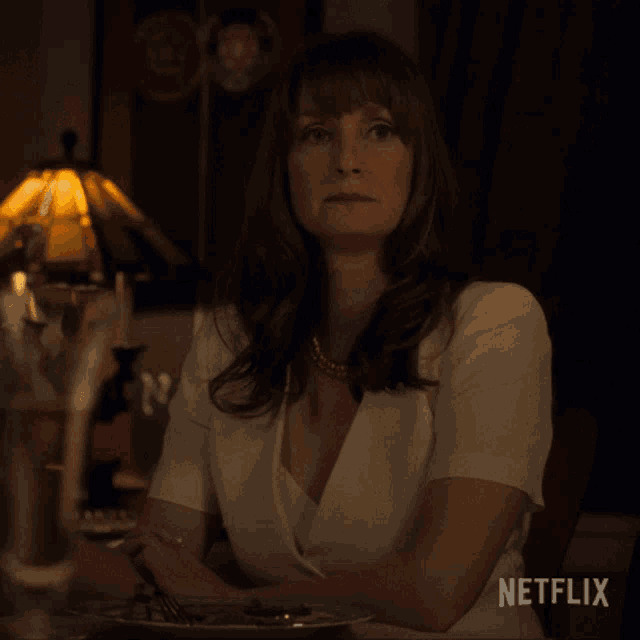 a woman sitting at a table with a plate of food and a netflix logo in the corner