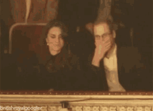 a man and a woman are sitting in a theatre with britishroyalgoogler written on the bottom right