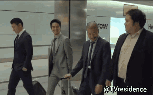 a group of men in suits and ties are walking down a hallway with a sign that says " row "