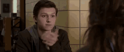 a young man is sitting at a table talking to a woman in a restaurant .