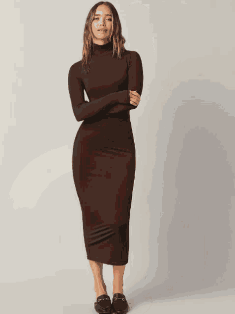 a woman is wearing a long brown dress with a turtleneck