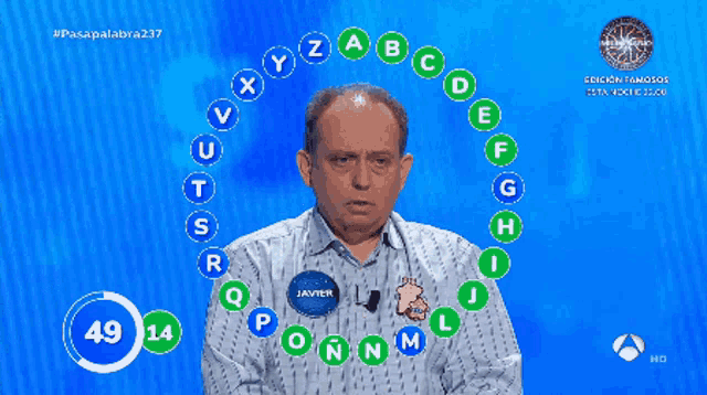 a man with a name tag that says javier stands in front of a blue background