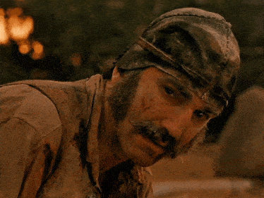 a man with a beard and mustache wearing a dirty hat