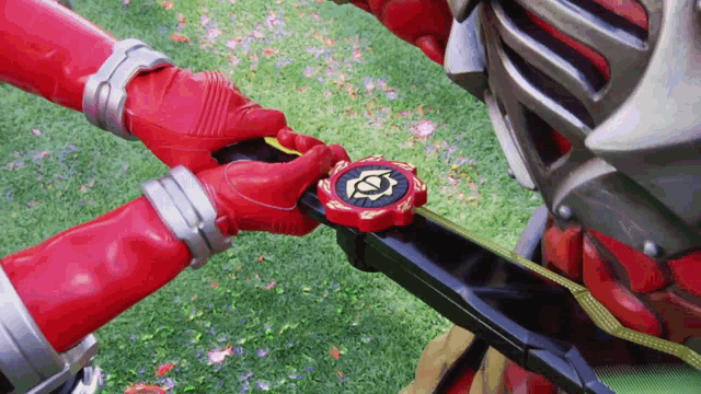 a person in a red glove is holding a red object with a yellow circle on it