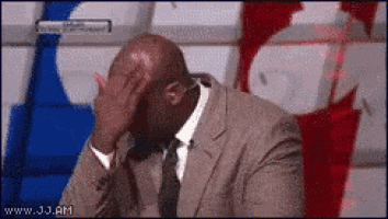 a man in a suit and tie covering his face with his hand .