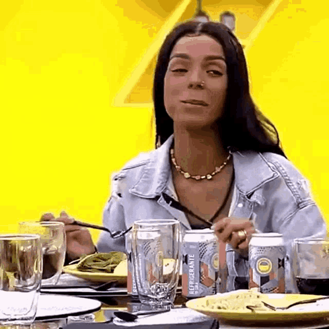 a woman is sitting at a table with a can of refrigerante beer in front of her .