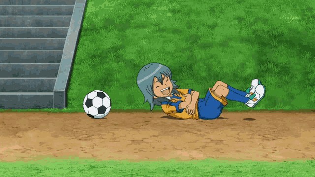 a soccer player is laying on the ground next to a ball