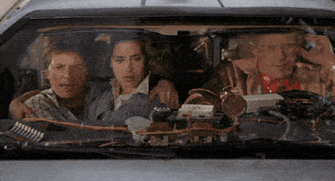 a group of people are sitting in a car with a clock on the dashboard that says ' clock ' on it