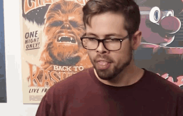 a man wearing glasses is standing in front of a poster that says back to kassie