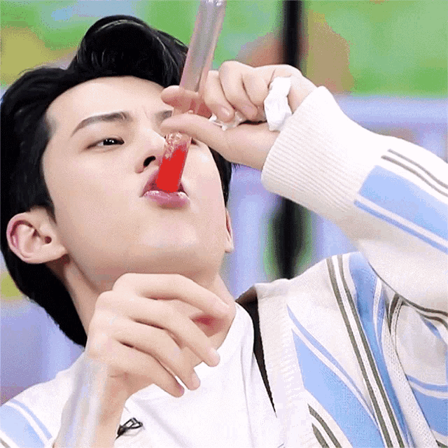 a man in a striped sweater is drinking from a tube