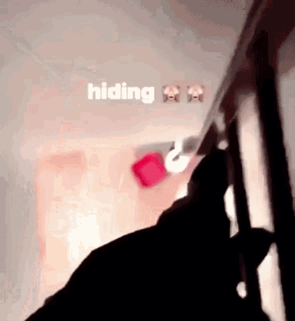 a person is hiding behind a staircase with the word hiding on the wall behind them .