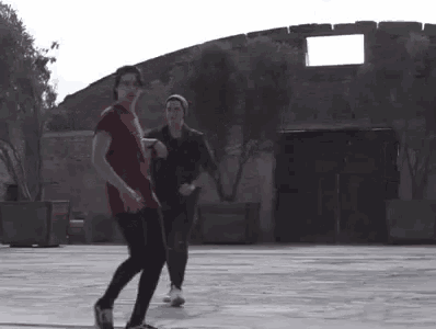 two men are dancing in front of a building in a courtyard .