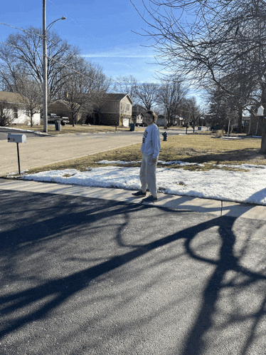 a man in a white sweatshirt is standing on the sidewalk