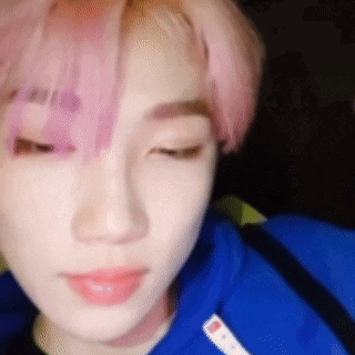 a close up of a person 's face with pink hair wearing a blue hoodie .